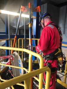 Support team members: man in red overalls PPE outside a confined space area