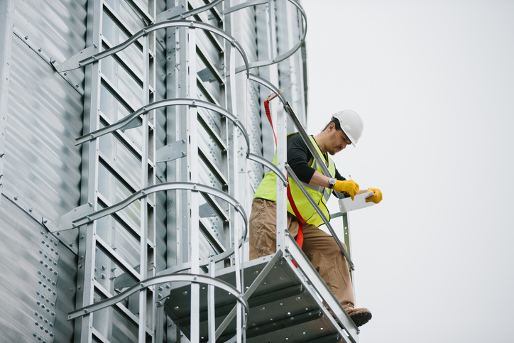 Working at height awareness course - Image of worker on a tall ladder outside of an industrial building